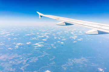 Fototapeta premium View from the airplane window at a beautiful cloudy sky and the airplane wing