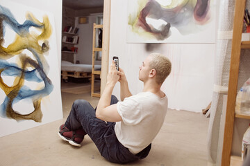Artist taking photo of his own painting in studio