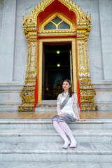 Portrait of beautiful young woman wearing Thai Rattanakosin national costume in a temple built according to Thai art in Thailand.