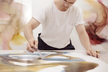 Working artist removing tape layer from painting