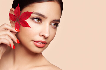 Fototapeta na wymiar Portrait of beautiful young woman with autumn leafs. Healthy clean fresh skin natural make up beauty eyes and red nails