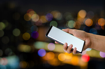 men or women hands holding on smartphone blank white screen at night colorful bokeh  background.