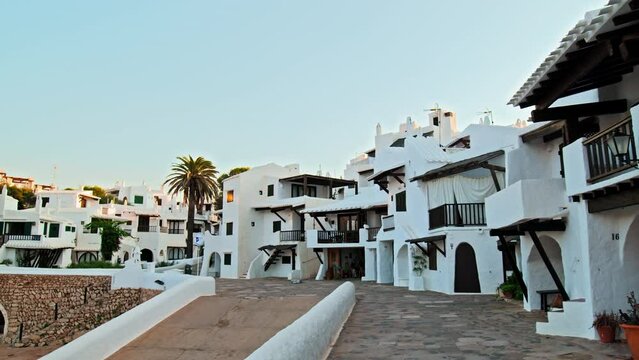 Binibeca Coastal Village with whitewashed houses with wooden windows and doors. Binibeca Vell a Calm Cove Resort with narrow streets overlooking Mediterranean Sea in Menorca, Balearic Islands, Spain.