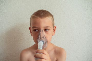 very sick sad boy who keeps respirator lungs, blows air out of the inhaler