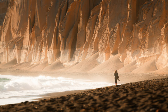 Volcanic Cliffs On Vlichada Beach In Santorini Island, Greece. Woman Walking Along The Beach.