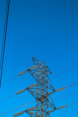 Electric towers and cables that stretch against a bright blue sky and clear sky background