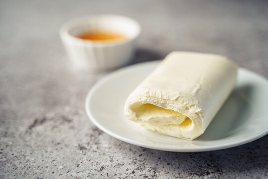 Close up picture of white cream milky kaymak butter roll poured with honey on plate.