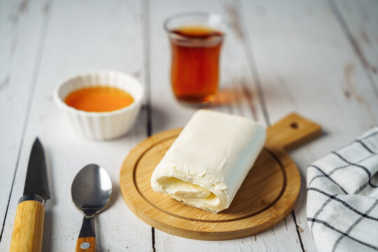 Close up picture of white cream milky kaymak butter roll poured tea on wooden plate.