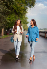 Two young women are walking around the city and talking.