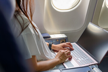 Business woman commercial plane passenger using laptop on board for working while sitting in...
