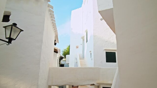 Narrow Whitewashed Streets in a tourist resort Binibeca Vell in Menorca, Spain. Beautiful small village town on the Balearic Islands with traditional brown wooden windows and doors in Europe.