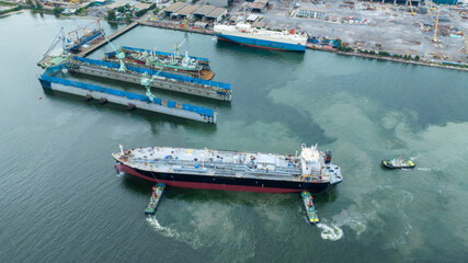 Tug boat pull cargo container ship from dry dock concept maintenance service working in the sea....