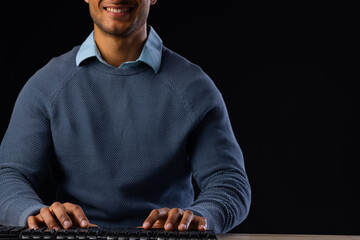 Biracial businessman using computer with copy space on black background