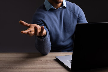 Biracial businessman using laptop and pointing with copy space on black background