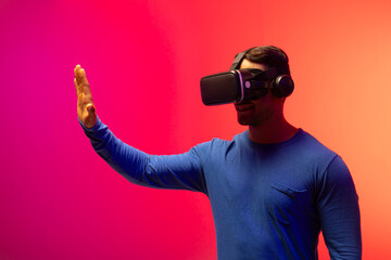 Biracial businessman using vr headset on neon pink to orange background