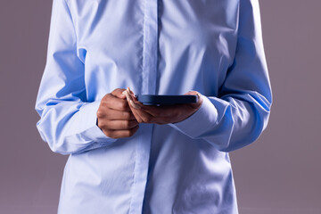 Biracial businesswoman using smartphone with copy space on grey background