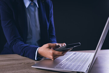 Biracial businesswoman using smartphone and laptop on black background