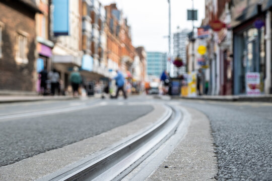 British high street shops close focused in tram tracks on the road- Croydon, South London