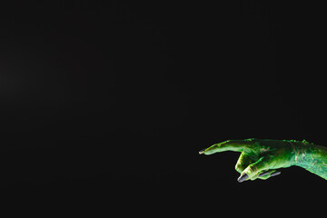 Obraz premium Green monster hand with black nails pointing with finger on black background