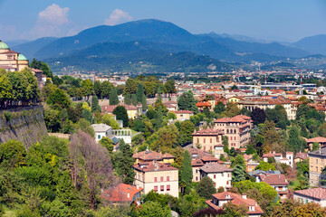 Fototapeta na wymiar Aerial view of the old town Bergamo in northern Italy with red tiled roofs of houses on the background of the Alpine mountains. Bergamo is a city in the alpine Lombardy region.