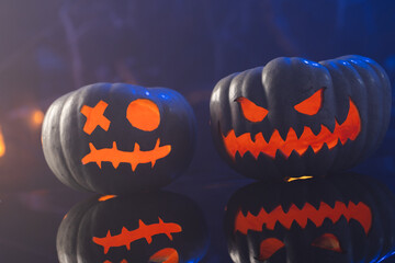 Fototapeta premium Two black carved pumpkins faces on blue background