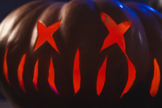 Fototapeta Carved pumpkin face illuminating with red light on black background