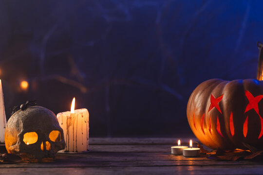 Fototapeta Carved pumpkin, skull and candle with copy space on dark background