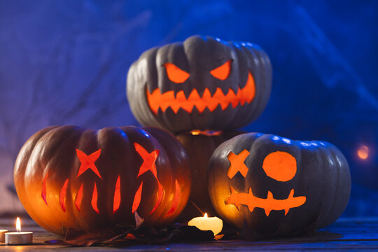 Fototapeta Three carved pumpkins and candles on blue background