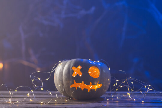 Fototapeta Carved pumpkin with led lights with copy space on blue background
