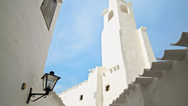 Binibeca Vell - a coastal village with narrow streets and whitewashed houses. White church tower on a summer sunny day in Menorca, Balearic Islands, Spain in 4k ProRes