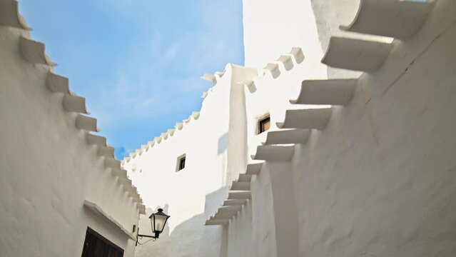 Binibeca Vell - a coastal village with narrow streets and whitewashed houses. White church tower on a summer sunny day in Menorca, Balearic Islands, Spain in 4k ProRes