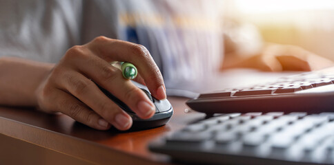 Closeup shot of a mouse holding a female hand and working with a desktop computer while sitting at a desk.