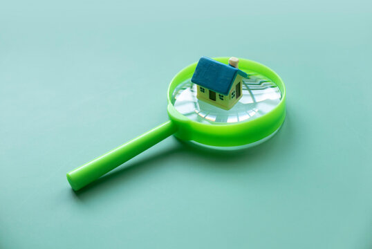 Eco friendly house concept. A miniature house on a green magnifying glass.