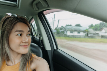 Asian Thai woman take selfie in car while traveling passenger on holidays, looking at the window.