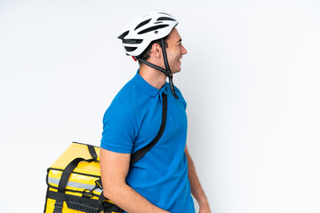 Young caucasian man with thermal backpack isolated on white background laughing in lateral position
