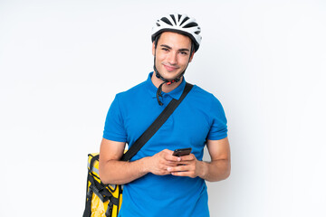 Young caucasian man with thermal backpack isolated on white background sending a message with the mobile