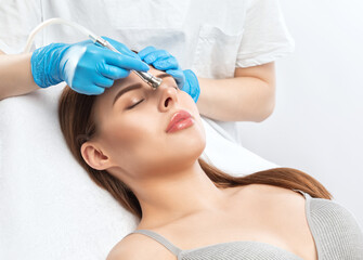 Beautiful brunette woman at the beautician.Cosmetologist does anti wrinkle injections on the face...