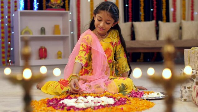 A cute little girl wearing a suit and decorating flower rangoli with flower petals  Indian tradition in festivals. Indian stock footage of a cute girl decorating her house for festive preparations ...