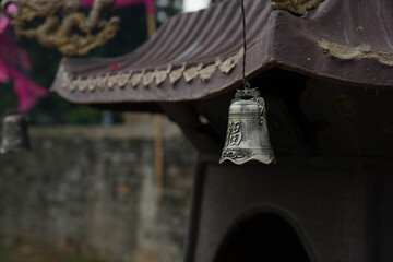 Bell hangs on the roof of a antique copper incense burner tower. Chinese traditional craft decor.