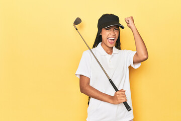 Indonesian female golfer on yellow backdrop raising fist after a victory, winner concept.