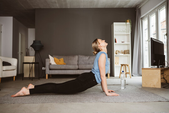 Young Woman Practicing Yoga on her Living Room Carpet