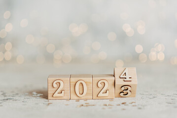 Beginning and start of the new year 2024. Preparation for happy new year ,new life, new business, plan, goals, strategy concept. Hand flips wooden cubes with to 2024 on smart background.