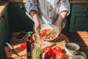 Young woman eating healthy food sitting in the beautiful interior with green flowers on the background