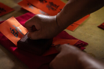 Writing prayers and blessings on red paper and stamping with buddha's name or temple seal. Traditional chinese folk custom for seeking blessings.