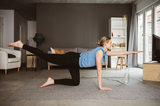 Young Woman Practicing Yoga on her Living Room Carpet