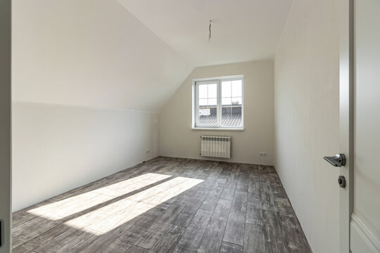 A room in a private house immediately after laying the floor, white unfinished walls and ceiling