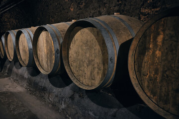 Row of wooden barrels bound with iron hoops in a bodega. Wine barrels made of oak at dark wine cellar. Wine cave at Beqaa valley, Lebanon