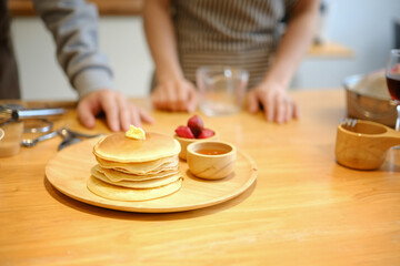 Tasty homemade pancakes with butter and maple syrup on wooden plate