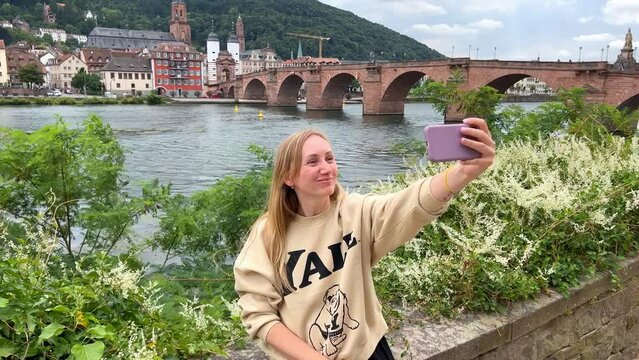 The girl takes pictures of herself on the phone against the background of the old city, communicates on the phone with friends, takes pictures of the city on a mobile phone, a tourist takes photos of 