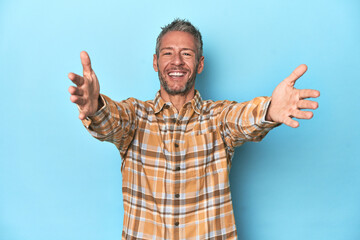Naklejka premium Middle-aged caucasian man on blue backdrop feels confident giving a hug to the camera.